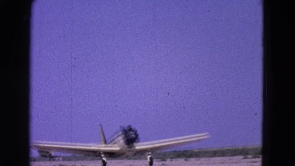 1964 Washington, DC area 8mm frame of a small propeller plane moving along the runway in a home-movie view.