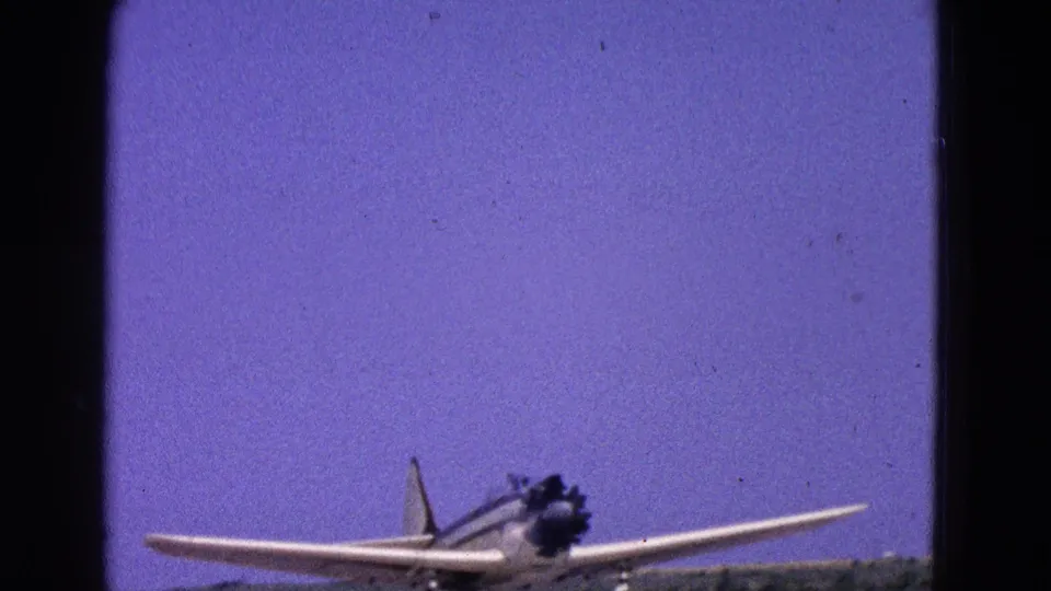 1964 8mm frame showing a small propeller aircraft angled on an airfield runway near Washington, DC.
