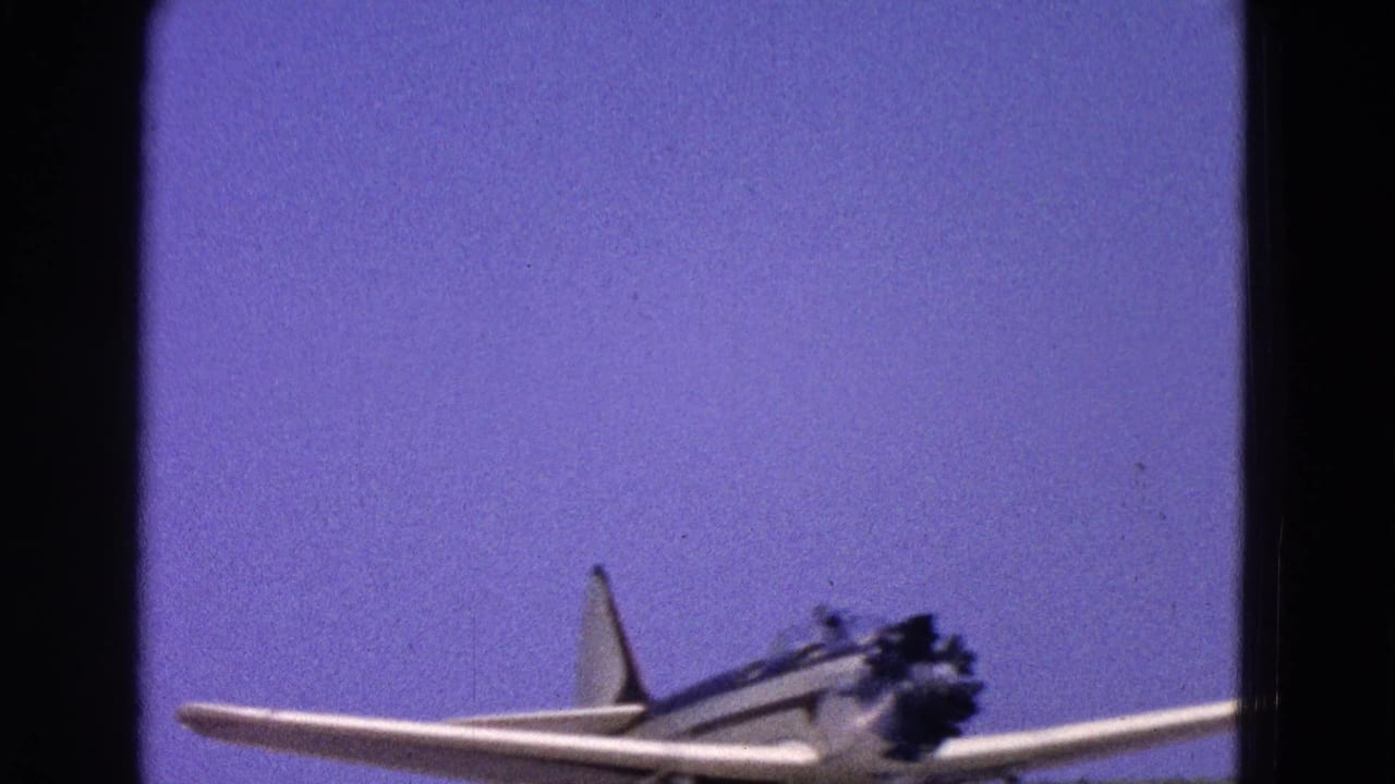 The small white aircraft remains low in frame as it moves along the runway in the 1964 Washington, DC home-movie footage.