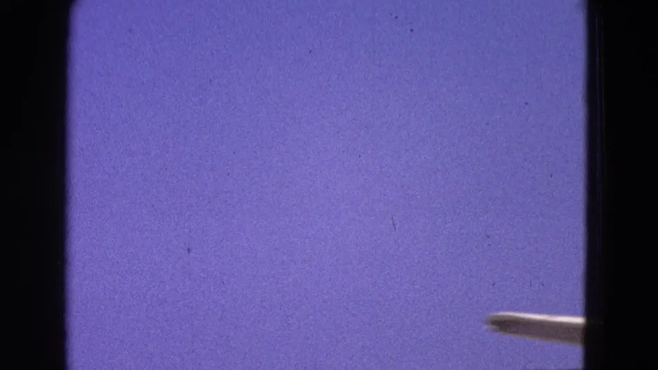 A brief 8mm frame dominated by sky, with only the aircraft wingtip visible at the lower right during takeoff movement.