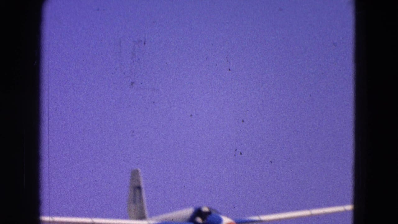 Glider nose, cockpit, wing, and tail rising against blue sky.