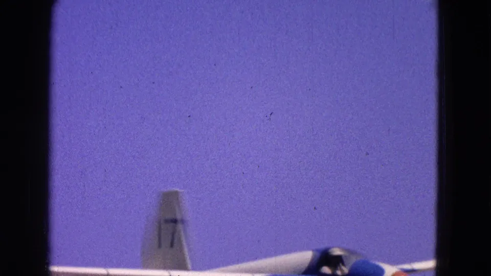 The glider crosses the lower frame with the number 17 visible on its tail and the pilot seated under the canopy.