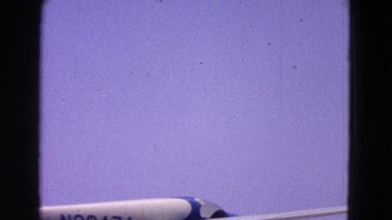 1964 Washington, DC frame with the blue and white airplane partly cropped as it moves across a pale sky.