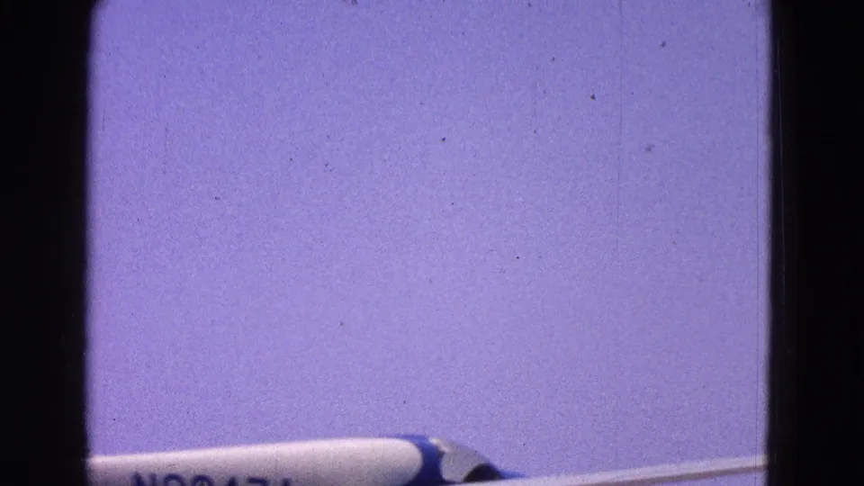 1964 Washington, DC frame with the blue and white airplane partly cropped as it moves across a pale sky.