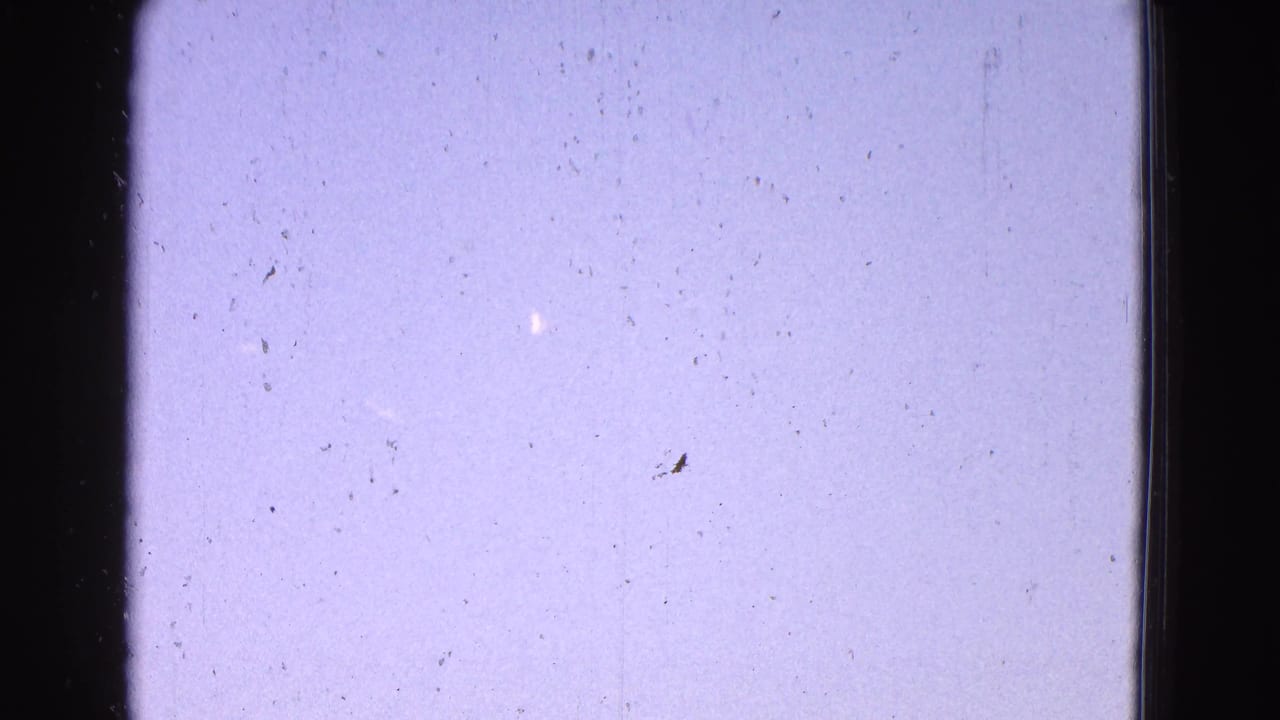 Bright sky framed by dark vertical film or window edges with dust specks visible.