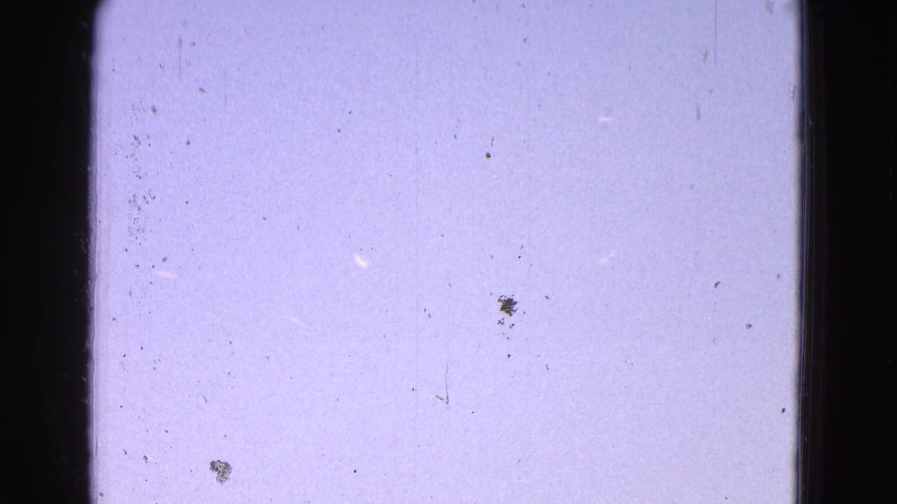 Bright blue-purple sky with dark vertical borders and scattered film dust.