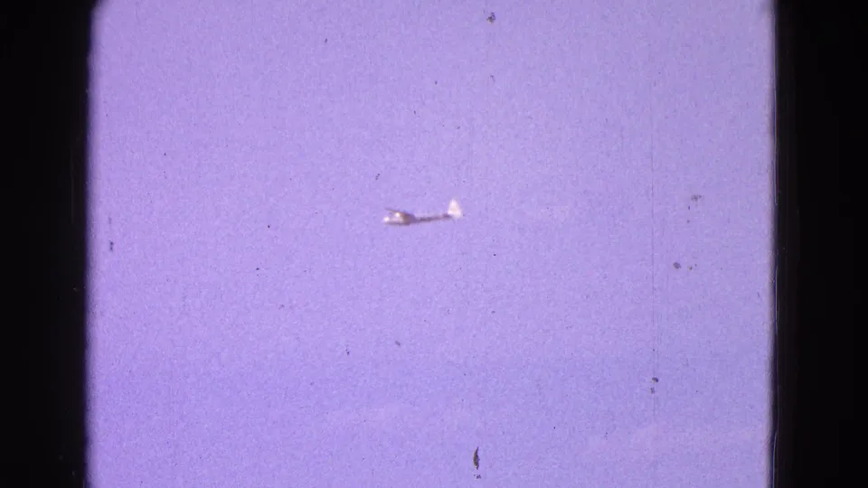 1964 Washington, DC area 8mm frame showing the small plane farther away against a hazy purple sky.