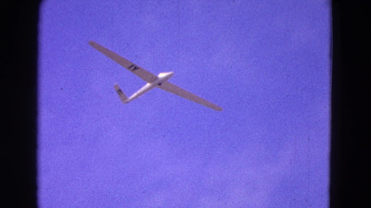 White glider banking slightly in open purple sky.