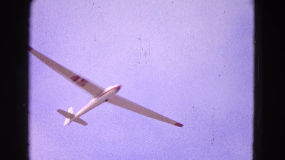 Closer 8mm view of the white glider banking in 1964 Washington, DC footage, with red markings and soft film grain.