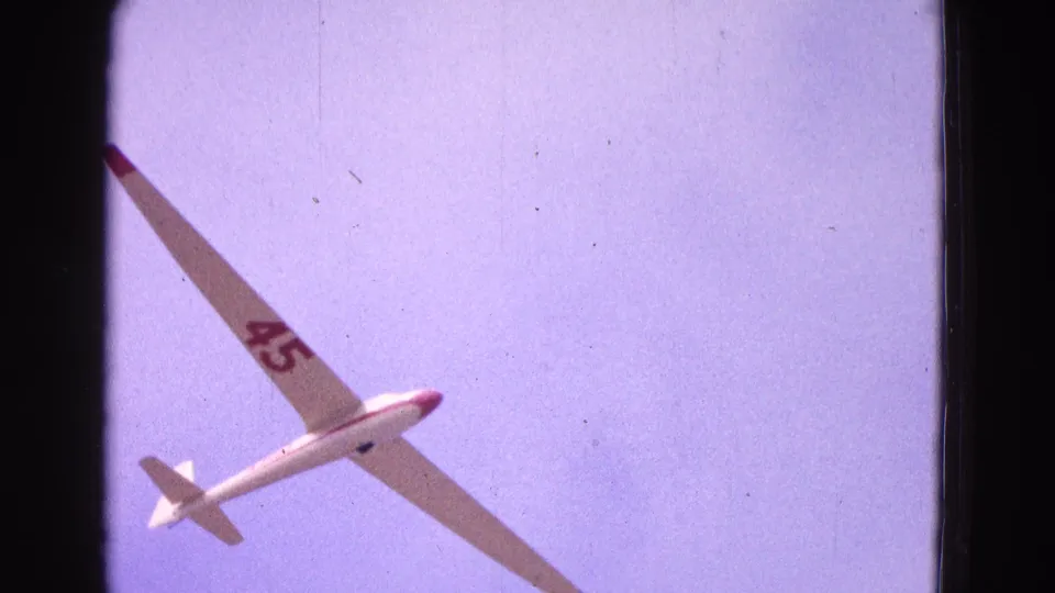 Final 1964 Washington, DC frame showing the glider banking diagonally, its red number 45 clear against the purple-blue sky.