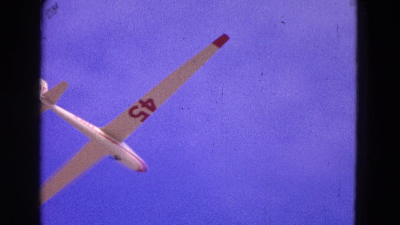 1964 8mm frame of a white glider marked 45 banking in a purple-blue sky over the Washington, DC area.