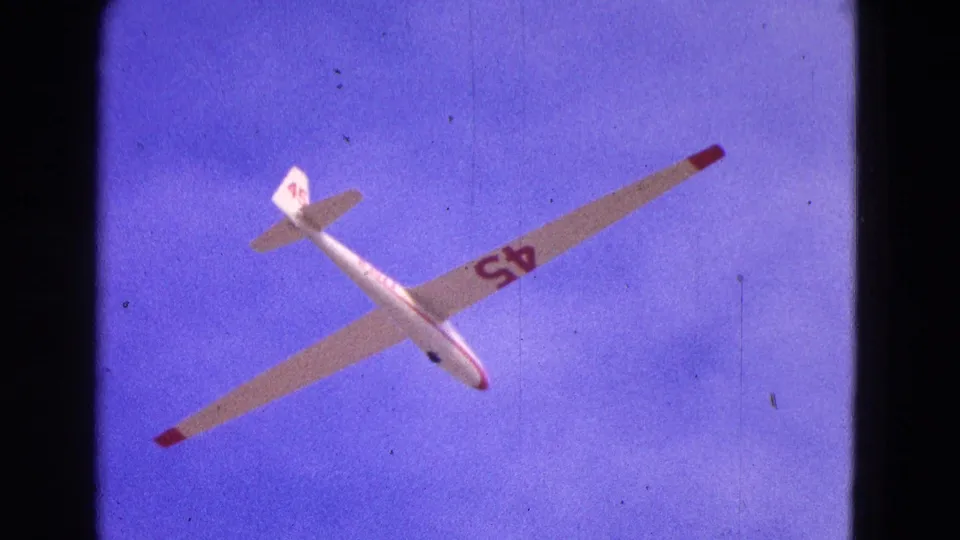 The glider appears overhead with long wings, red tips, and the number 45 visible on the wing in this 1964 home-movie frame.
