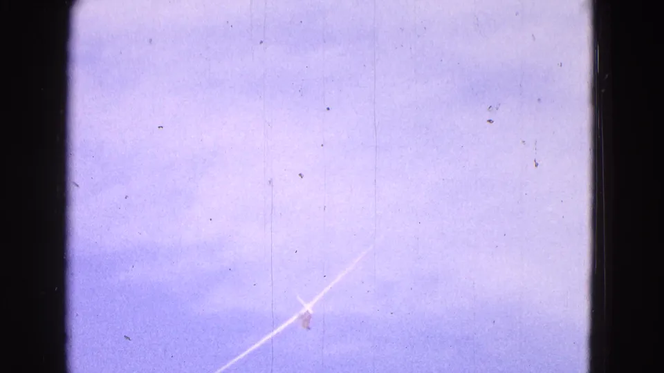 A distant white glider appears small against a cloudy blue sky near the end of the 1964 home-movie clip.
