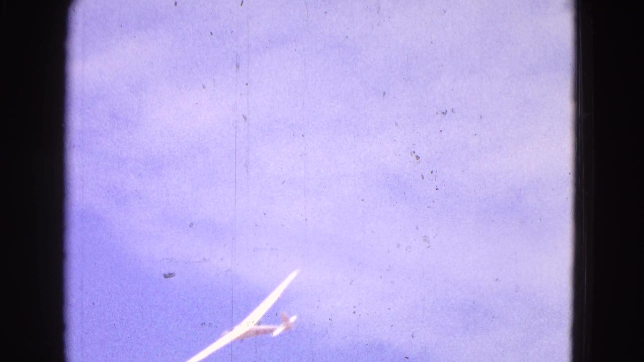 White glider near the lower edge of a blue sky frame.