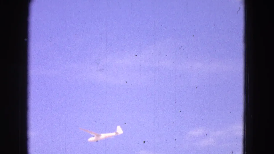A 1964 8mm view of a white glider passing through the lower sky, with Washington, DC supplied by clip metadata.