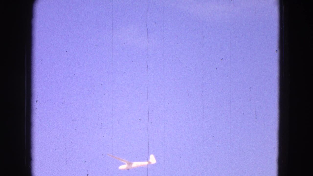 A small white glider appears low against a faded blue-purple sky in 1964 8mm home-movie footage from the Washington DC metadata context.