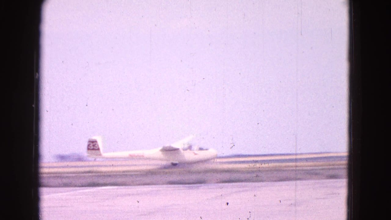 Small white glider moving along a runway with a tail number visible.