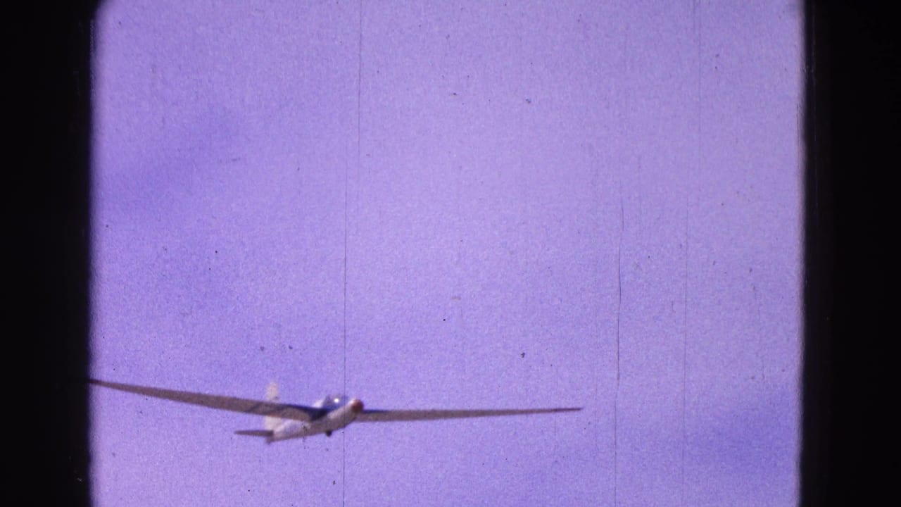 A white glider with long wings approaches through a purple-blue sky in 1964 8mm home-movie footage from Washington, DC metadata.