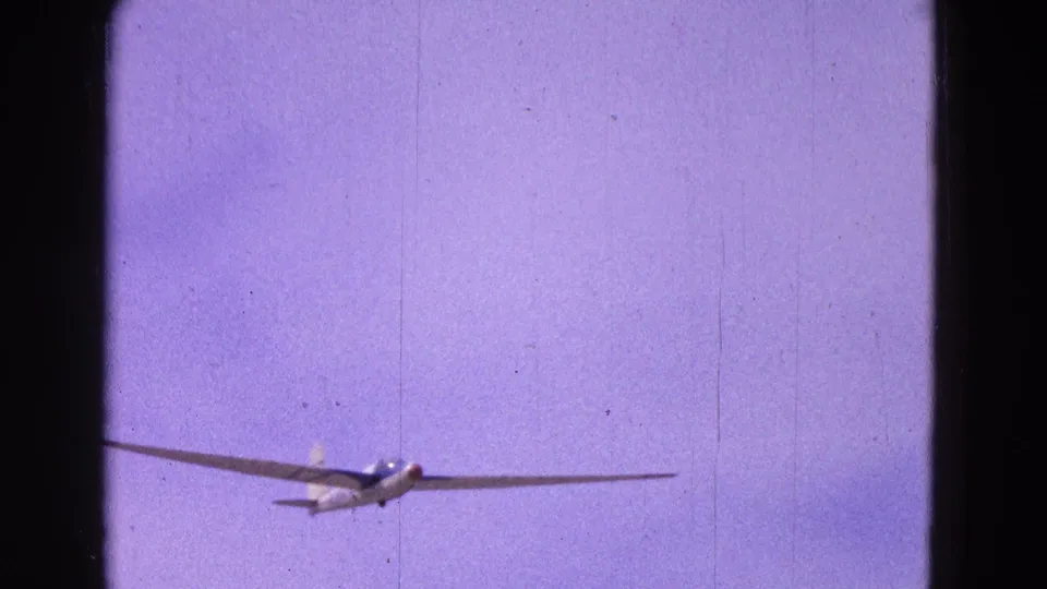 A white glider with long wings approaches through a purple-blue sky in 1964 8mm home-movie footage from Washington, DC metadata.
