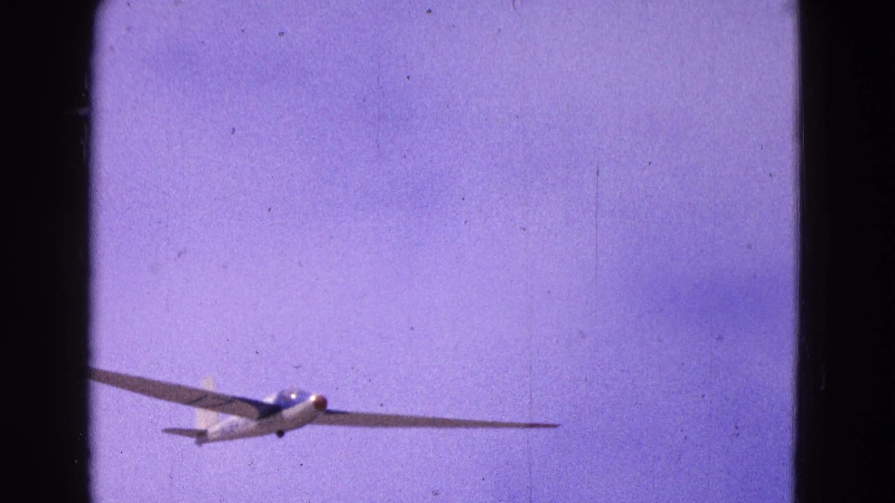 The glider crosses the frame with its long wings visible against a purple-blue sky, consistent with the 1964 aviation home-movie metadata.