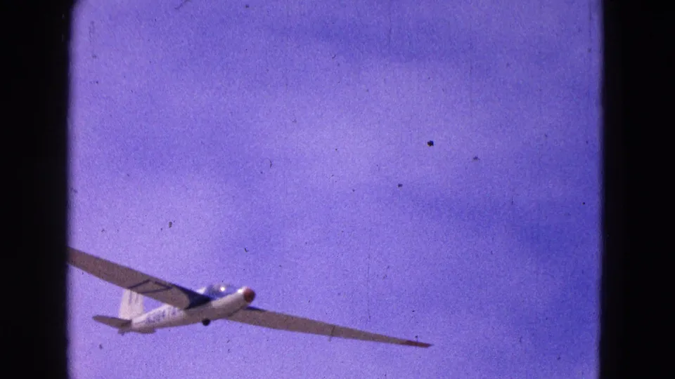 A closer 8mm frame shows the white glider with a red nose and visible tail number 17 against the purple-blue sky.