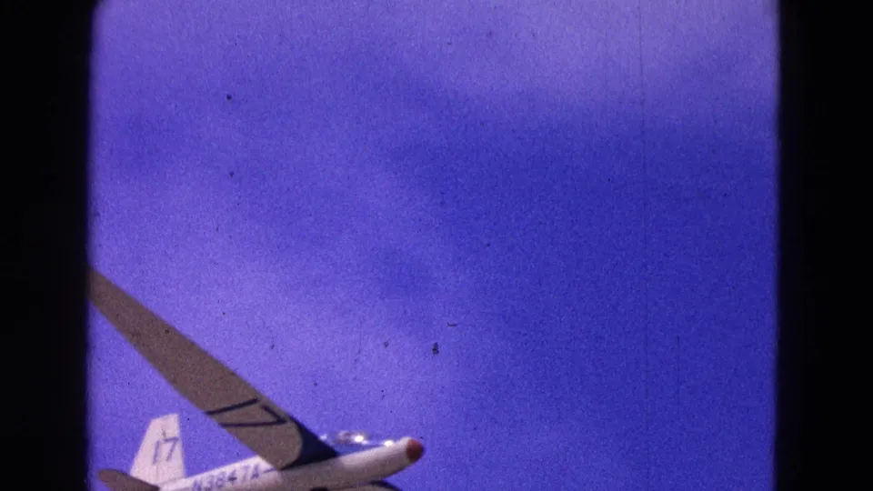 1964 8mm frame of a white glider with tail number 17 crossing a deep blue sky in the Washington, D.C. clip.