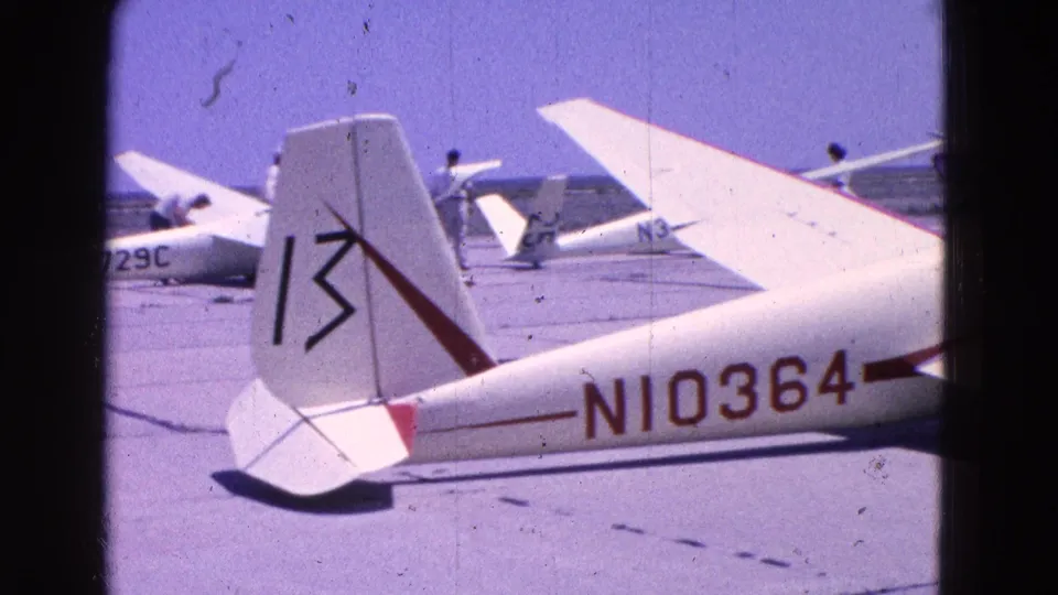 Glider tail marked 13 and fuselage N10364 appear beside another small aircraft marked N6729C on the tarmac.
