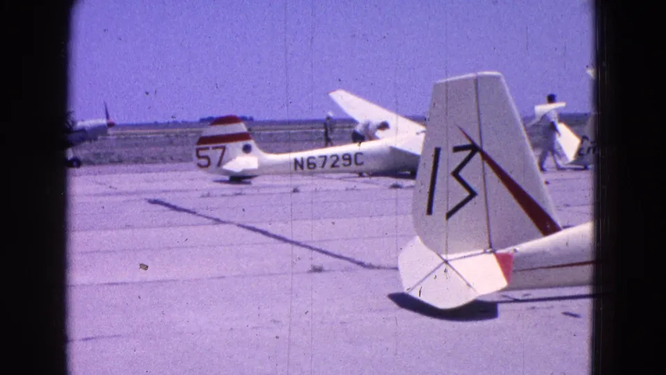 1964 Washington, DC airfield frame with a small aircraft marked N6729C behind a cropped foreground tail and open tarmac.