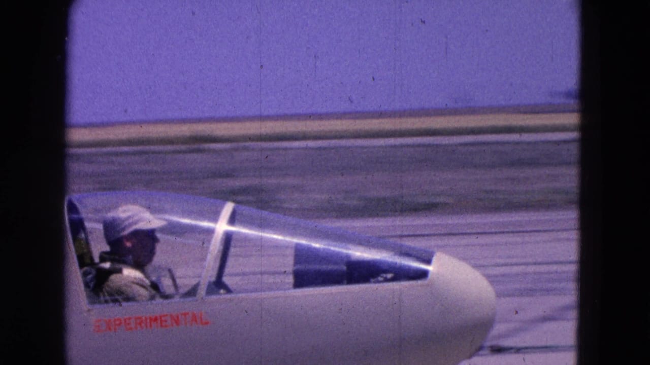 Small experimental aircraft cockpit with pilot on a runway.