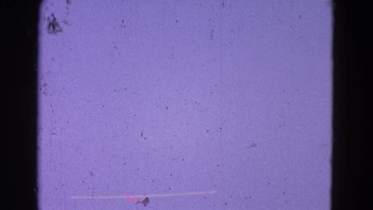 1964 8mm home-movie frame from Washington, DC area showing a small aircraft low in frame beneath a purple-blue sky.