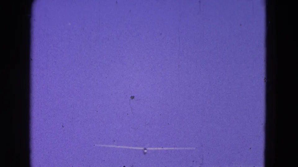 Distant glider crosses the sky above open land in the 1964 Washington, DC metadata clip, framed through grainy 8mm film.