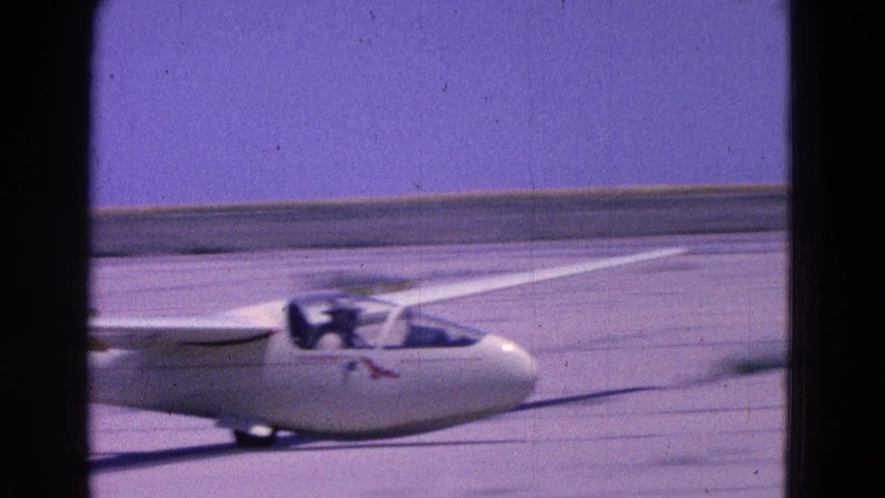 Side view of the white glider taxiing on a runway in supported 1964 Washington DC home-movie footage.