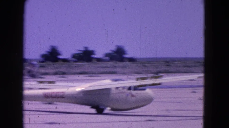 1964 8mm frame of a white glider beginning its takeoff run at a rural airfield near Washington, DC.