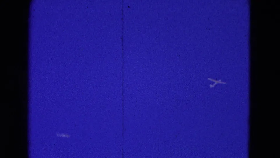 Distant aircraft are visible against a deep blue 8mm sky, with dark gate edges and film texture from the 1964 Washington, DC clip.