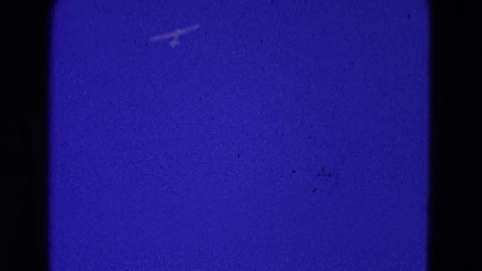 A distant small aircraft appears as a faint pale mark in a blue sky, from 1964 Washington, DC home-movie footage.
