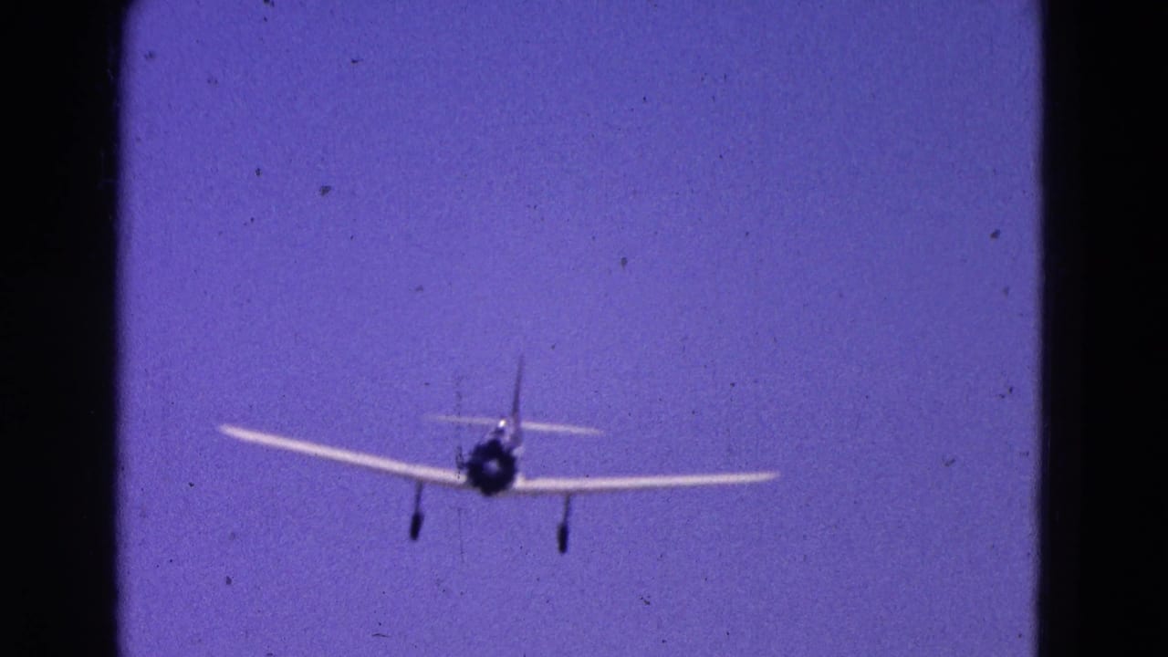 Small propeller airplane approaches against a purple-blue sky with landing gear down.