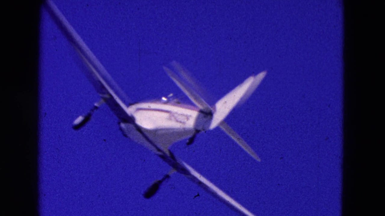 White small plane flying through a deep blue sky with dark 8mm frame edges.
