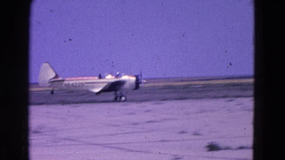 The small two-seat aircraft rolls along the runway after landing, with occupants or cockpit shapes faintly visible.