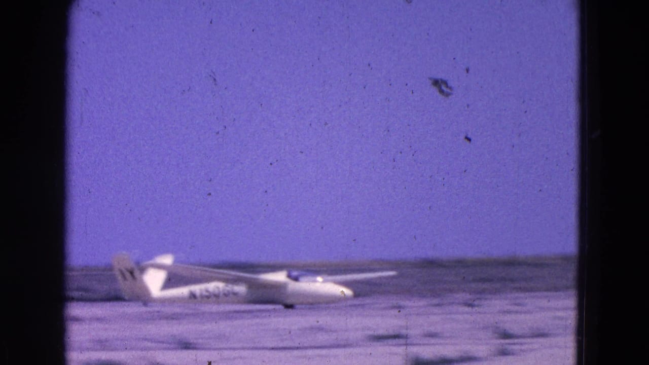 White glider on a runway under a purple-tinted sky.
