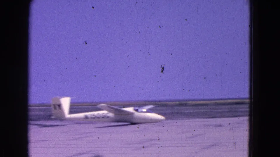 The glider appears to move along the runway in the 1964 home-movie footage, with its nose low and tail markings visible.