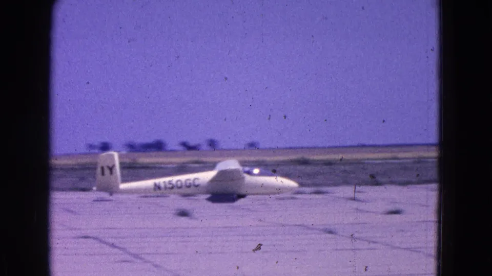 Side view of the white glider on the runway, with N150GC visible on the fuselage and IY on the tail.
