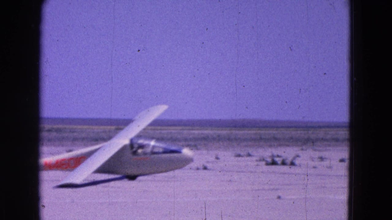 White glider seen from the side on a pale runway surface.