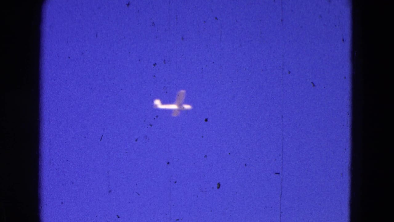 Small airplane silhouetted against a deep blue-purple sky.