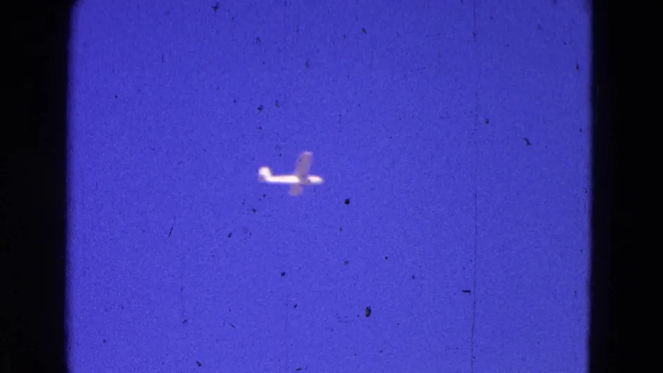 A small light aircraft crosses a color-shifted 8mm sky in the Washington, DC airport footage.