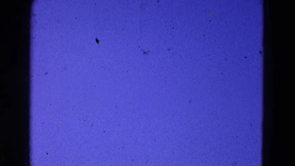 A 1964 8mm home-movie sky frame shows a small distant plane against deep blue sky with visible film grain and dust.