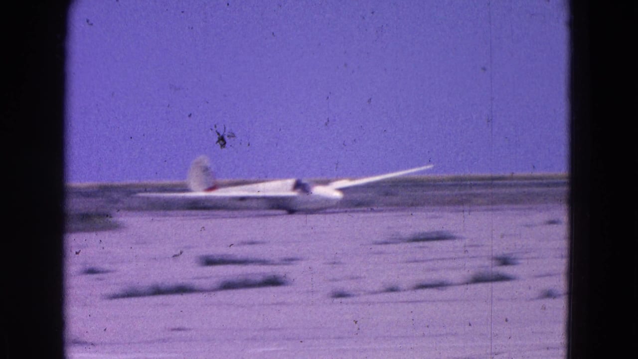 White glider rolling across the airfield with its long wing visible.