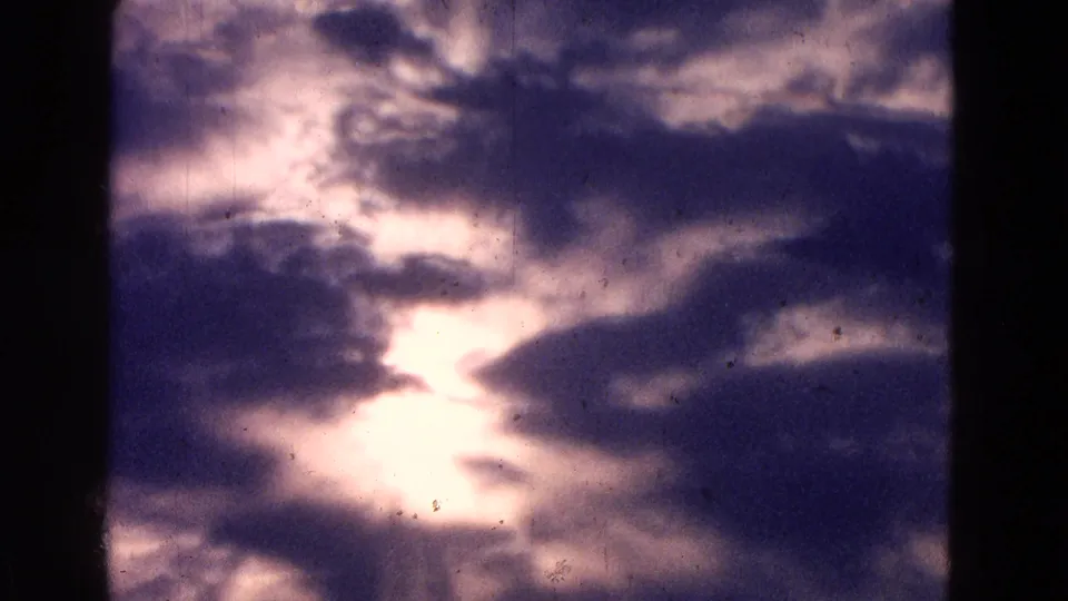 Stormy sky over the Washington DC aviation footage, with sunlight glowing through dark clouds on 8mm film.