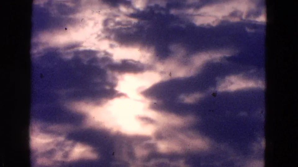Final 1964 8mm frame showing a bright opening in heavy clouds, likely filmed during the same airfield sequence.