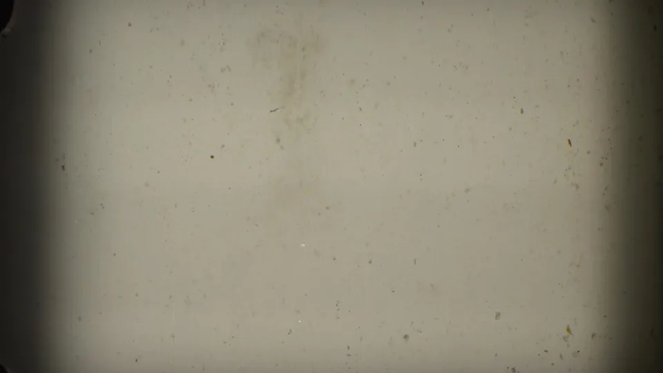 Mostly blank 8mm film frame with warm exposure, visible gate edge, dust, and film wear before the airfield scene appears.