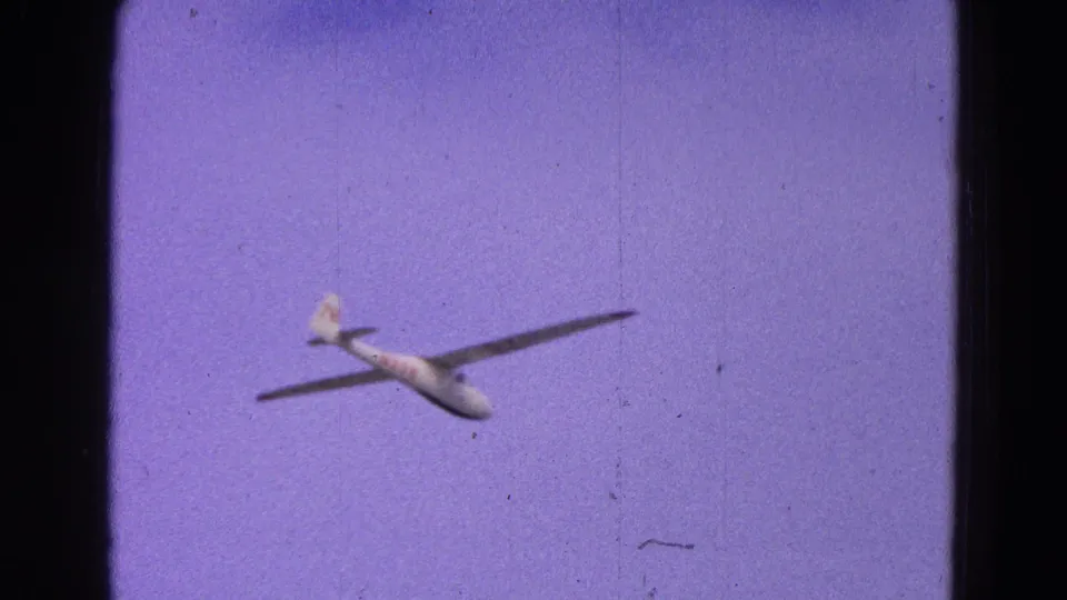The glider appears smaller and more distant while banking across a pale purple sky in the closing 8mm frame.